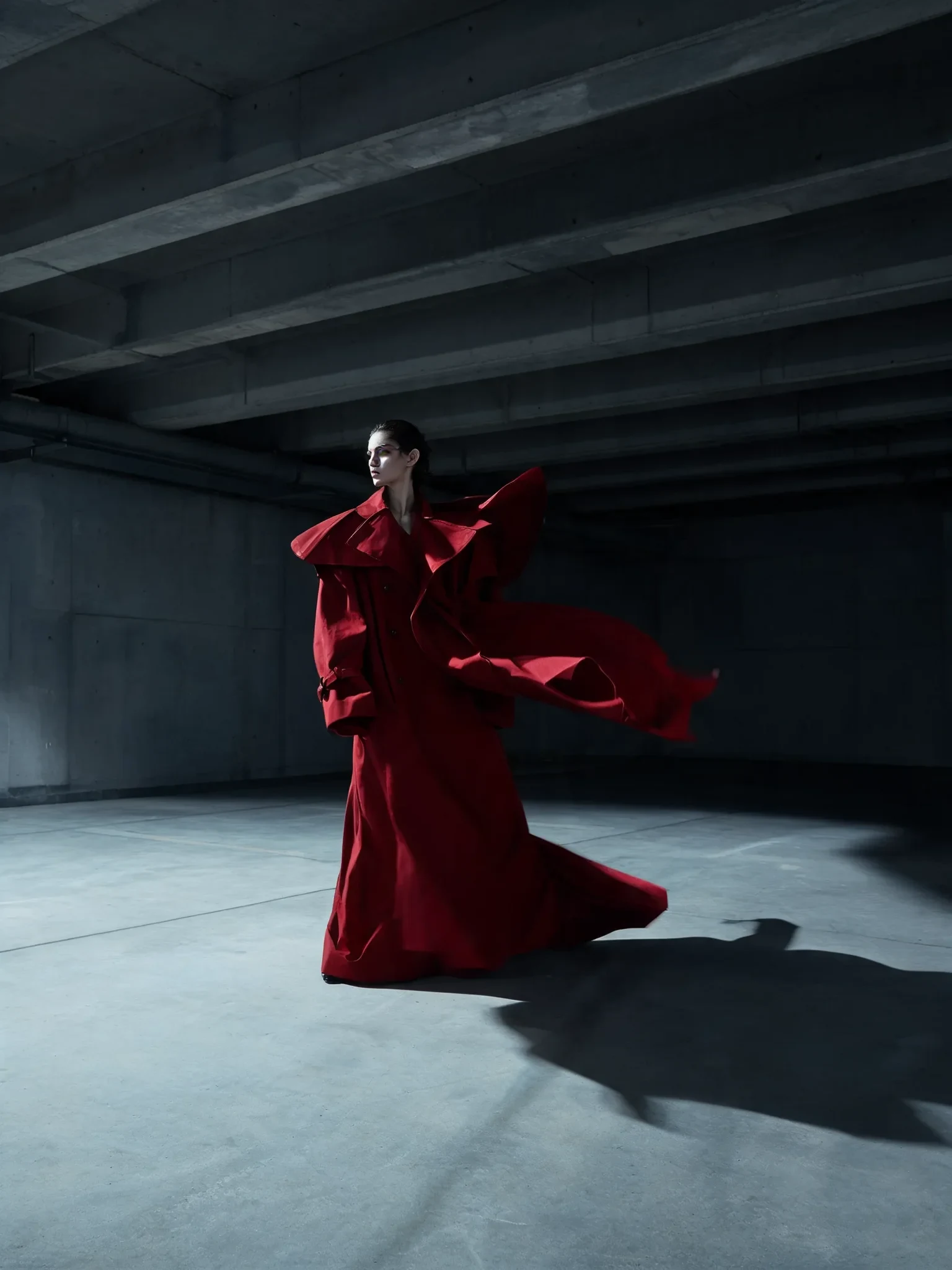 Fashion editorial portrait with a flowing crimson coat